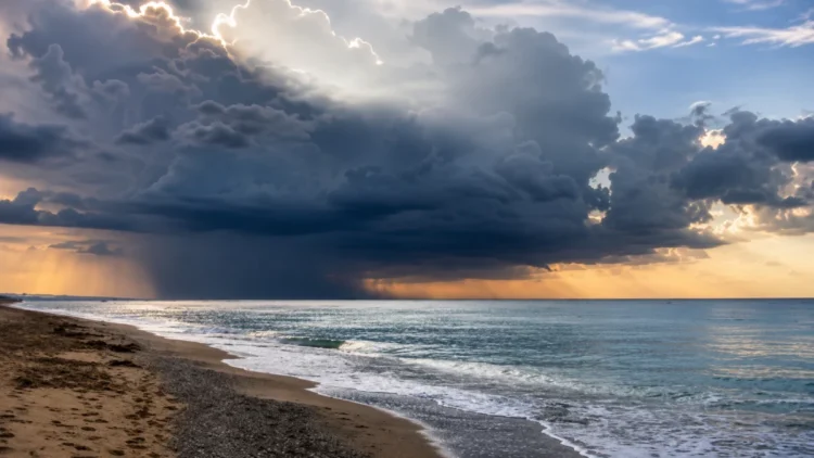 Nuvole temporalesche sul mare della Sicilia con rovesci in lontananza e cielo parzialmente illuminato.