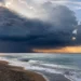 Nuvole temporalesche sul mare della Sicilia con rovesci in lontananza e cielo parzialmente illuminato.