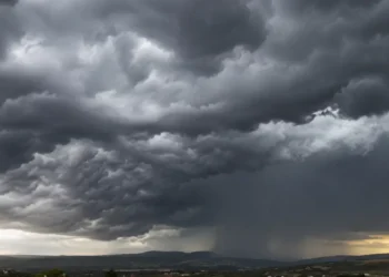 Nuvole temporalesche scure sopra il paesaggio siciliano con precipitazioni in lontananza
