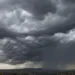 Nuvole temporalesche scure sopra il paesaggio siciliano con precipitazioni in lontananza
