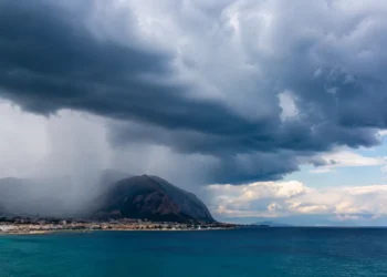 Panorama della costa siciliana con nubi temporalesche e pioggia in avvicinamento sul mare e sulle montagne.