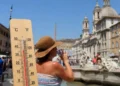 Turisti e fontana in una giornata di forte caldo con termometro in primo piano e temperature elevate