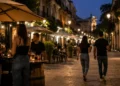 Vista di una zona urbana con locali e persone durante una serata estiva, a rappresentare la regolamentazione della movida.
