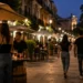 Vista di una zona urbana con locali e persone durante una serata estiva, a rappresentare la regolamentazione della movida.
