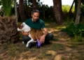 Il tecnico ortopedico Pietro Di Falco accarezza la pitbull Kim mostrando la protesi in TPU viola stampata in 3D applicata alla zampa posteriore sinistra, nel giardino del canile di Chiaramonte Gulfi