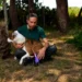 Il tecnico ortopedico Pietro Di Falco accarezza la pitbull Kim mostrando la protesi in TPU viola stampata in 3D applicata alla zampa posteriore sinistra, nel giardino del canile di Chiaramonte Gulfi