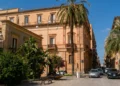 Veduta del centro di Vittoria con edifici storici e palme lungo una strada cittadina