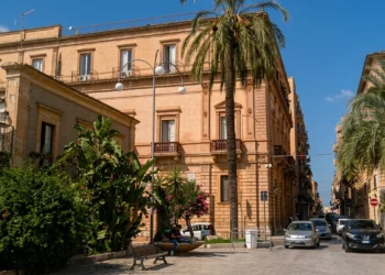 Veduta del centro di Vittoria con edifici storici e palme lungo una strada cittadina