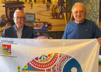 Due rappresentanti locali mostrano la bandiera REIMAR durante un'iniziativa dedicata alle identità marinare siciliane.
