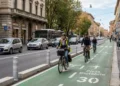 Ciclisti lungo una strada con infrastrutture dedicate alla mobilità sicura e traffico veicolare ordinario.
