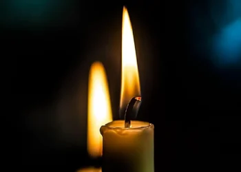 Candela accesa su sfondo scuro, immagine simbolica di lutto e cordoglio.