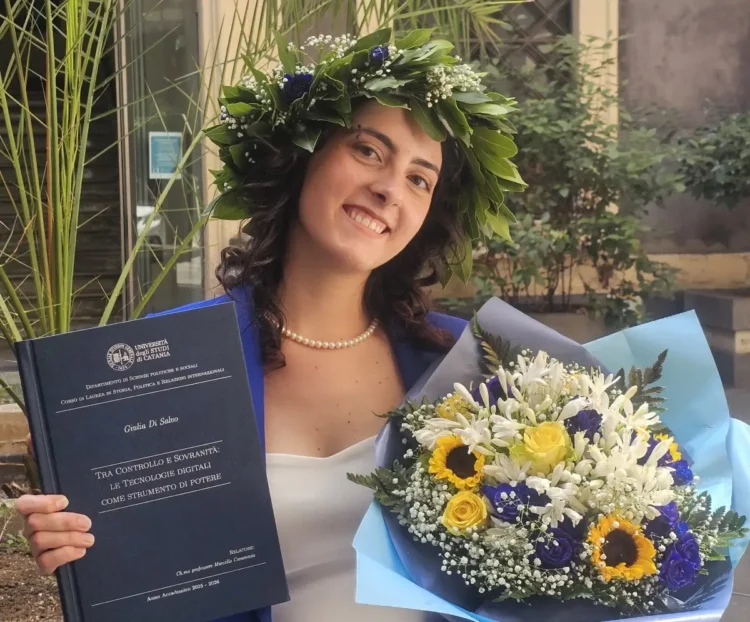Giulia Di Salvo posa con la tesi di laurea e un mazzo di fiori dopo aver conseguito la laurea in Scienze Politiche con 110 e lode all'Università di Catania