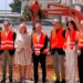 I rappresentanti di Sibeg Coca-Cola, delle istituzioni e dei partner industriali durante la posa della prima pietra del nuovo polo logistico automatizzato nello stabilimento di Catania, con un escavatore sullo sfondo.