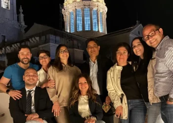 Componenti del gruppo consiliare IdeAzione posano in una foto di gruppo in piazza a Comiso, con la cupola della chiesa illuminata sullo sfondo durante una serata.