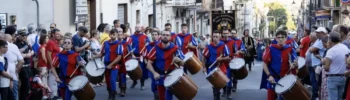 I Tamburi di Giarratana in costume medievale sfilano durante il MeMuFest lungo una strada del centro storico, accompagnati dal pubblico