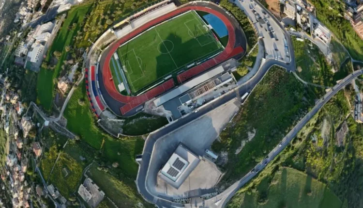 Vista aerea dello stadio Pietro Scollo di Modica con il campo da calcio, la pista di atletica e il settore della curva destinato ai tifosi ospiti.