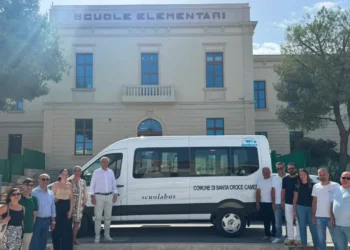 Il nuovo scuolabus elettrico del Comune di Santa Croce Camerina davanti all'edificio delle scuole elementari con il sindaco, amministratori e personale comunale durante la consegna