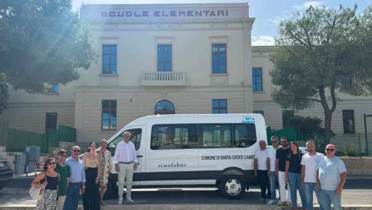 Il nuovo scuolabus elettrico del Comune di Santa Croce Camerina davanti all'edificio delle scuole elementari con il sindaco, amministratori e personale comunale durante la consegna