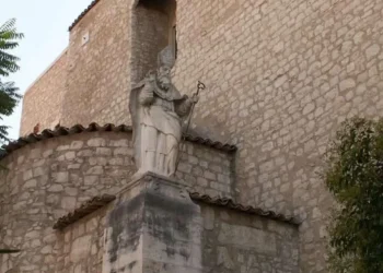 La statua di San Biagio collocata davanti alla chiesa dedicata al patrono di Comiso, con la facciata in pietra dell'edificio religioso sullo sfondo