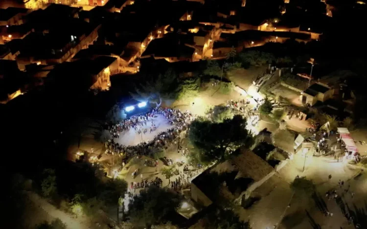 Veduta aerea serale di una precedente edizione del MeMuFest a Giarratana con il pubblico riunito nell'area degli spettacoli.