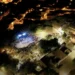 Veduta aerea serale di una precedente edizione del MeMuFest a Giarratana con il pubblico riunito nell'area degli spettacoli.
