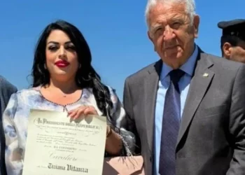 Tiziana Vitanza mostra il diploma di Cavaliere dell'Ordine al Merito della Repubblica Italiana accanto a Corrado Di Stefano durante la cerimonia.