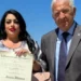 Tiziana Vitanza mostra il diploma di Cavaliere dell'Ordine al Merito della Repubblica Italiana accanto a Corrado Di Stefano durante la cerimonia.