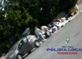 Persona accanto a un cumulo di rifiuti abbandonati lungo una strada a Ragusa durante un controllo della Polizia Locale
