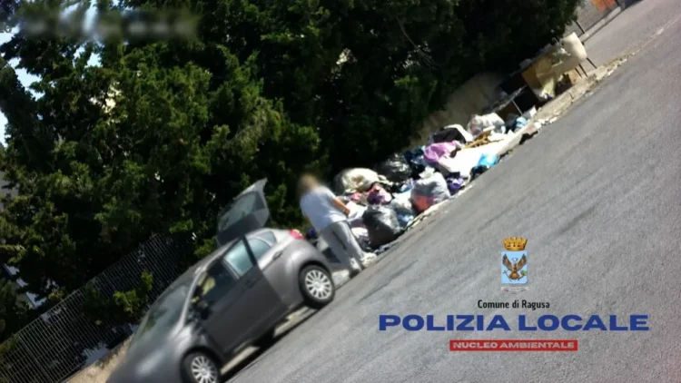 Persona accanto a un cumulo di rifiuti abbandonati lungo una strada a Ragusa durante un controllo della Polizia Locale
