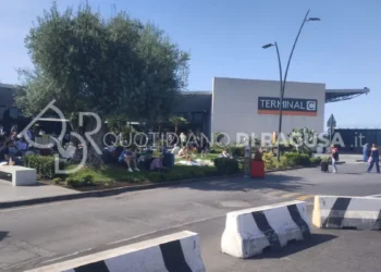 Passeggeri seduti e in attesa davanti al Terminal C dell'aeroporto di Catania dopo la sospensione dei voli causata dall'attività dell'Etna