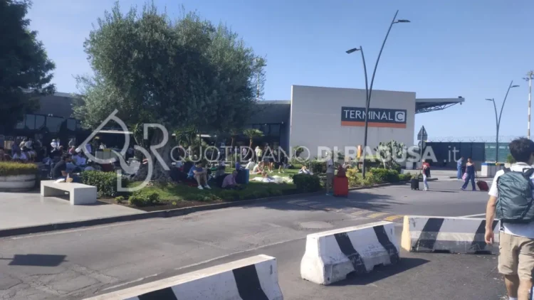 Passeggeri seduti e in attesa davanti al Terminal C dell'aeroporto di Catania dopo la sospensione dei voli causata dall'attività dell'Etna