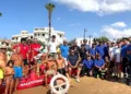 Bagnini, carabinieri e volontari della protezione civile in posa sulla spiaggia accanto a un pattino di salvataggio