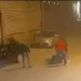 Fermo immagine da telecamera di sorveglianza: due uomini aggrediscono una persona a terra in una strada notturna