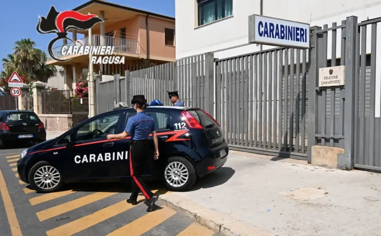 Auto dei Carabinieri parcheggiata davanti al cancello della Stazione Carabinieri di Pozzallo, con due militari in divisa