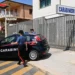 Auto dei Carabinieri parcheggiata davanti al cancello della Stazione Carabinieri di Pozzallo, con due militari in divisa