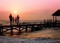 Una famiglia passeggia su un pontile al tramonto sul mare, immagine simbolica dell'assegno unico destinato ai nuclei con figli.