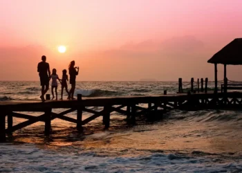 Una famiglia passeggia su un pontile al tramonto sul mare, immagine simbolica dell'assegno unico destinato ai nuclei con figli.