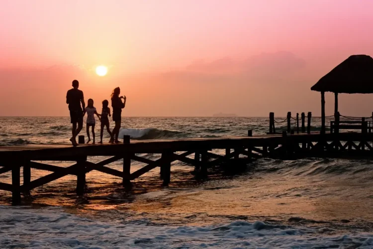 Una famiglia passeggia su un pontile al tramonto sul mare, immagine simbolica dell'assegno unico destinato ai nuclei con figli.