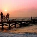 Una famiglia passeggia su un pontile al tramonto sul mare, immagine simbolica dell'assegno unico destinato ai nuclei con figli.