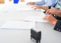 Persone impegnate nella firma di documenti durante un'assunzione, immagine rappresentativa degli incentivi per le assunzioni a tempo indeterminato previsti nel 2026.