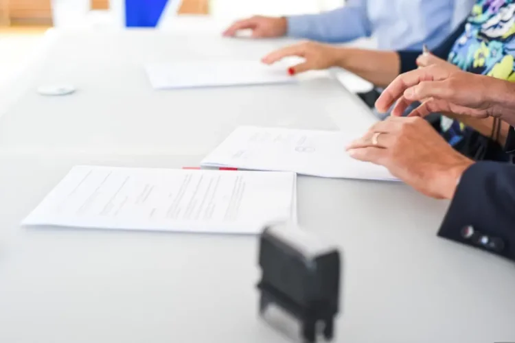 Persone impegnate nella firma di documenti durante un'assunzione, immagine rappresentativa degli incentivi per le assunzioni a tempo indeterminato previsti nel 2026.