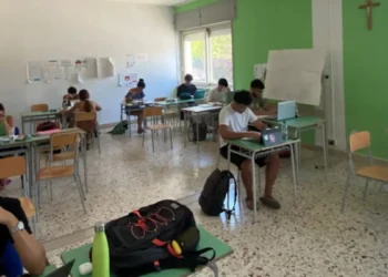 Studenti impegnati nello studio all'interno dell'aula studio estiva di Marina di Ragusa, con postazioni individuali e computer portatili.