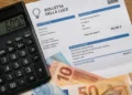 Calcolatrice, bolletta della luce e banconote in euro su un tavolo, immagine rappresentativa del bonus bollette 2026 fino a 60 euro
