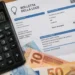 Calcolatrice, bolletta della luce e banconote in euro su un tavolo, immagine rappresentativa del bonus bollette 2026 fino a 60 euro