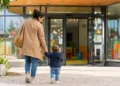 Genitore accompagna un bambino all'ingresso di un asilo nido in una mattina di sole