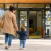 Genitore accompagna un bambino all'ingresso di un asilo nido in una mattina di sole