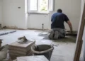Operaio posa nuove piastrelle durante la ristrutturazione di un'abitazione.
