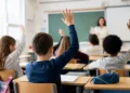 Studenti in aula durante una lezione con la mano alzata, immagine utilizzata per illustrare il bonus 2026 destinato alle famiglie con figli iscritti alle scuole paritarie