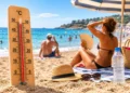Termometro oltre i 45 °C su una spiaggia siciliana con bagnanti di spalle durante un'intensa ondata di caldo.