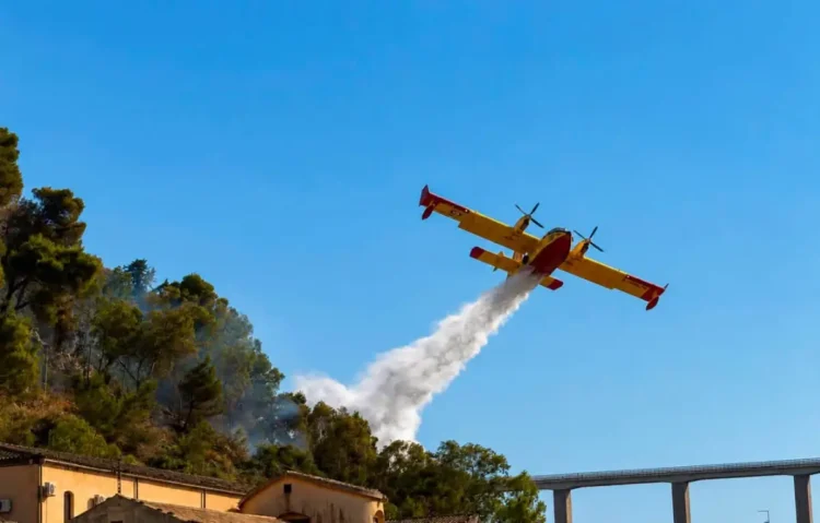 Canadair effettua un lancio d'acqua sulle fiamme dell'incendio che interessa la collina di Monserrato a Modica.